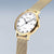 Montre femme de profil : cadran blanc avec index, boîtier doré, bracelet milanais