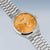 Montre homme avec cadran orange et bracelet en acier inoxydable argenté, vue de biais