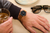 Armbanduhr am Handgelenk mit braunem Lederarmband und schwarzem Zifferblatt