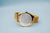 Seitenansicht der goldfarbenen Armbanduhr mit silbernem Zifferblatt und Milanaiseband