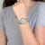 Montre pour femme au poignet avec bracelet argenté, accents dorés et cadran rond