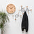 Horloge murale avec boîtier en bois clair et aiguilles noires à côté de patères