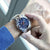 Montre chronographe pour homme au poignet : cadran bleu avec bracelet en métal argenté.