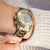 Montre femme au poignet avec cadran blanc, accents dorés et bracelet en acier inoxydable