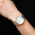 Montre pour femme au poignet avec bracelet en métal argenté et cadran blanc