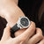 Montre pour femme au poignet avec bracelet en cuir noir et cadran noir, boîtier argenté