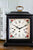 Vue de face : horloge de table avec bordure florale, chiffres romains et points dorés