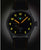 Montre homme avec bracelet en cuir noir et boîtier argenté ; cadran sombre avec chiffres jaunes