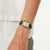 Damenarmbanduhr mit rechteckigem Gehäuse, weißem Zifferblatt und schwarzem Lederarmband