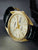 Herrenarmbanduhr im Seitenblick: schwarzes Lederband, goldfarbener Gehäuse, creme Zifferblatt