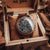 Herrenuhr im Holzsetzkasten: schwarzes Zifferblatt, braune Holzdetails, Chronograph
