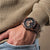 Holzkern Herrenarmbanduhr am Handgelenk: braunes Holzband, schwarzes Chronographenzifferblatt