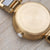 Rückseite einer goldfarbenen Armbanduhr mit Gravur auf Edelstahlgehäuse