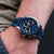 Herrenuhr auf dem Handgelenk mit blauem Zifferblatt, Chronographen-Zählern und Lederband