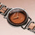 Herrenarmbanduhr mit rundem Gehäuse, braunem Leder-/Holzoptik-Zifferblatt und Metallband