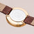 Damenuhr-Rückseite in Gold mit Gravur und Saphirschrift, am braunen Lederarmband