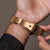 Goldfarbene Holzkern Armbanduhr am Handgelenk mit Meshband und Schließe