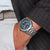 Armbanduhr von Holzkern am Handgelenk, silbernes Metallband, blau-schwarzes Zifferblatt