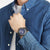 Herren Chronograph-Armbanduhr am Handgelenk mit blauem Zifferblatt und schwarzem Kautschukband.