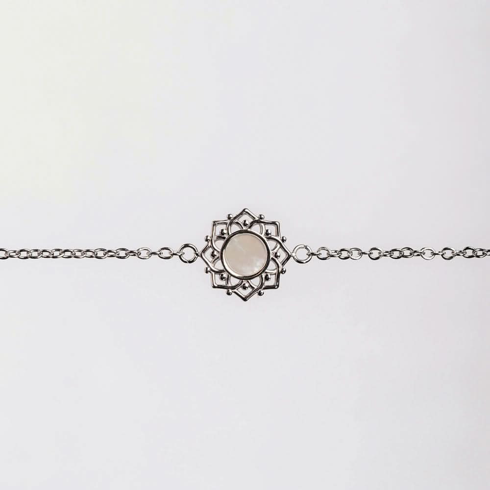 Bracelet avec chaîne à maillons argentés et pendentif rond en nacre dans un cadre ornemental