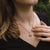 Collier au cou : chaîne dorée avec pendentif rond en bois devant un haut noir