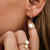 Puces d'oreilles dorées avec pendentif rond et insert blanc à l'oreille