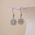 Boucles d'oreilles argentées avec flocon de neige et centre bleu, chacune avec un crochet