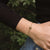 Bracelet au poignet avec chaîne dorée et pendentif rond en bois