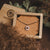 Collier avec pendentif rond dans un plateau en bois, motif de rayons avec centre rond.