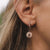 Puces d'oreilles sur l'oreille avec pendentif rond scintillant et créole dorée
