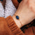 Bracelet gourmette doré avec pendentif ovale bleu au poignet