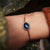 Bracelet doré avec pendentif ovale en cabochon bleu au poignet