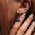 Puce d'oreille dorée avec pierre ovale bleue et fermoir crochet