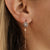Boucle d'oreille avec pierre ronde dans une couronne florale, chaîne pendante et fermoir à aiguille