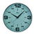 Horloge murale ronde avec bord argenté, cadran turquoise, chiffres arabes et verre.