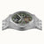 Herrenarmbanduhr von vorn: sichtbares Automatik-Uhrwerk hinter Glas, silbernes Gehäuse.