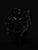 Montre homme avec cadran noir et aiguilles lumineuses, vue sombre