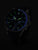 Montre homme dans l'obscurité : aiguilles et chiffres lumineux verts sur cadran noir