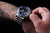 Montre pour homme au poignet avec lunette bleue, cadran noir et bracelet en acier inoxydable