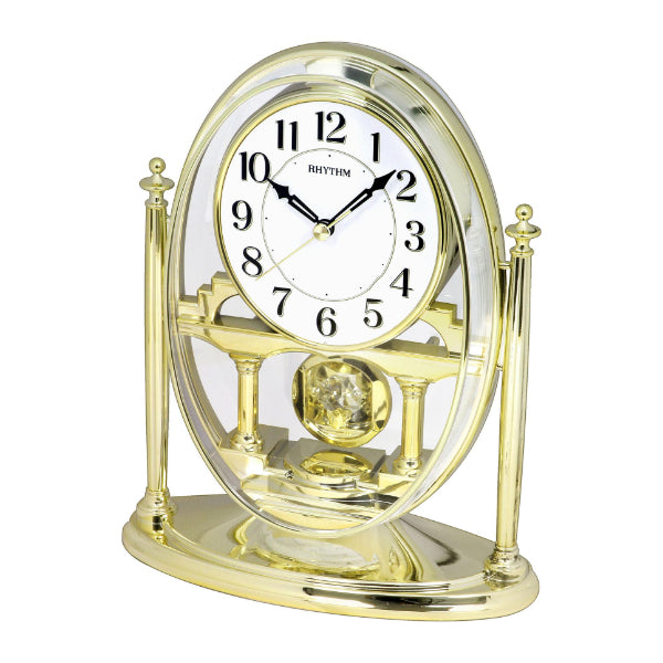 Horloge de table dorée avec cadran rond, grands chiffres arabes et mouvement décoratif.