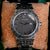 HOLZKERN-Armbanduhr mit dunkelgrauem Zifferblatt, reliefverziertem Gehäuse und Metallarmband