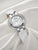 Bulova Damenuhr mit weißem Armband und silberner Lünette mit Ziersteinen, Nahansicht