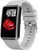 Smartwatch mit rechteckigem Display und hellgrauem Silikonarmband, seitlich.
