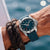 Montre pour homme au poignet : bracelet en silicone bleu, cadran bleu foncé avec aiguilles rouges.
