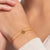 Bracelet doré au poignet avec pierres blanches et petit pendentif