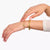 Bracelet jonc en plaqué or avec breloque rose au poignet
