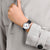 Damenuhr am Handgelenk mit schwarzem Lederarmband und weißem Zifferblatt