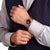 Herrenuhr am Handgelenk mit schwarzem Zifferblatt und roségoldfarbenem Metallband