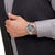 Herrenuhr am Handgelenk: silberfarbenes Metallarmband, graues Zifferblatt mit roten Zeigern