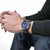 Montre homme au poignet avec bracelet en caoutchouc noir, cadran bleu et boîtier en métal.